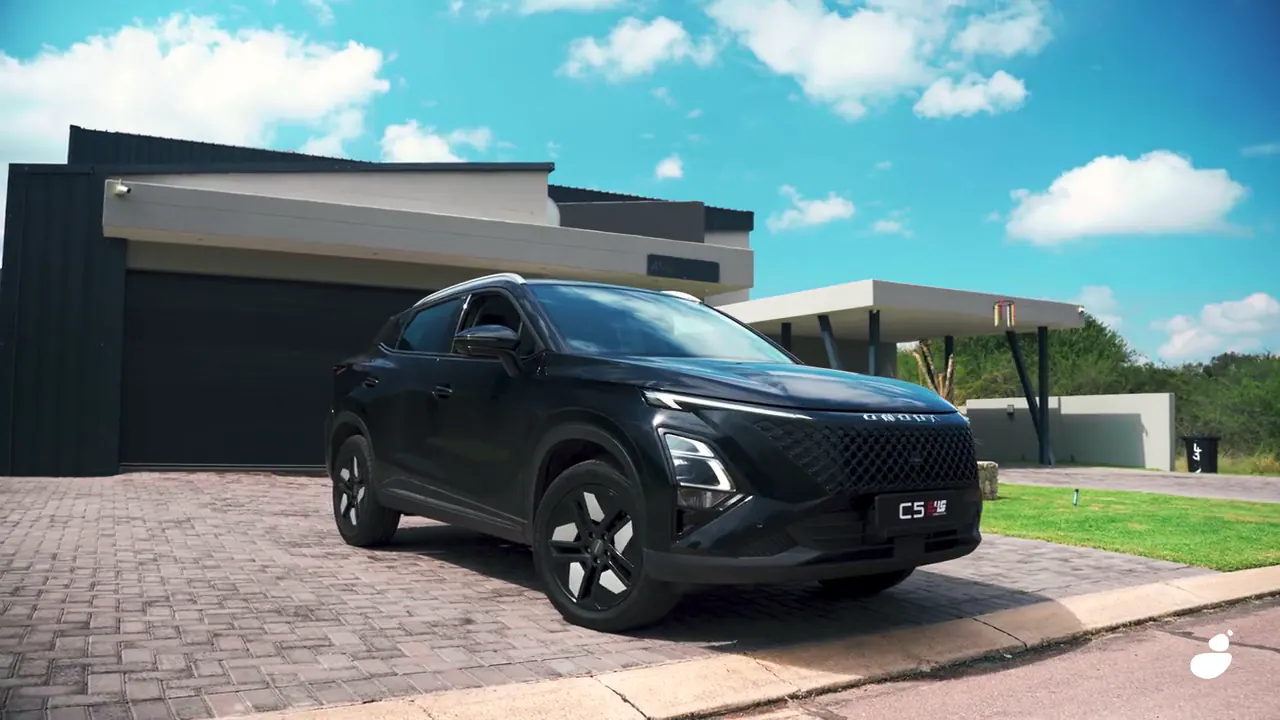 Black Omoda C5 on the paved driveway of a modern house under a blue sky