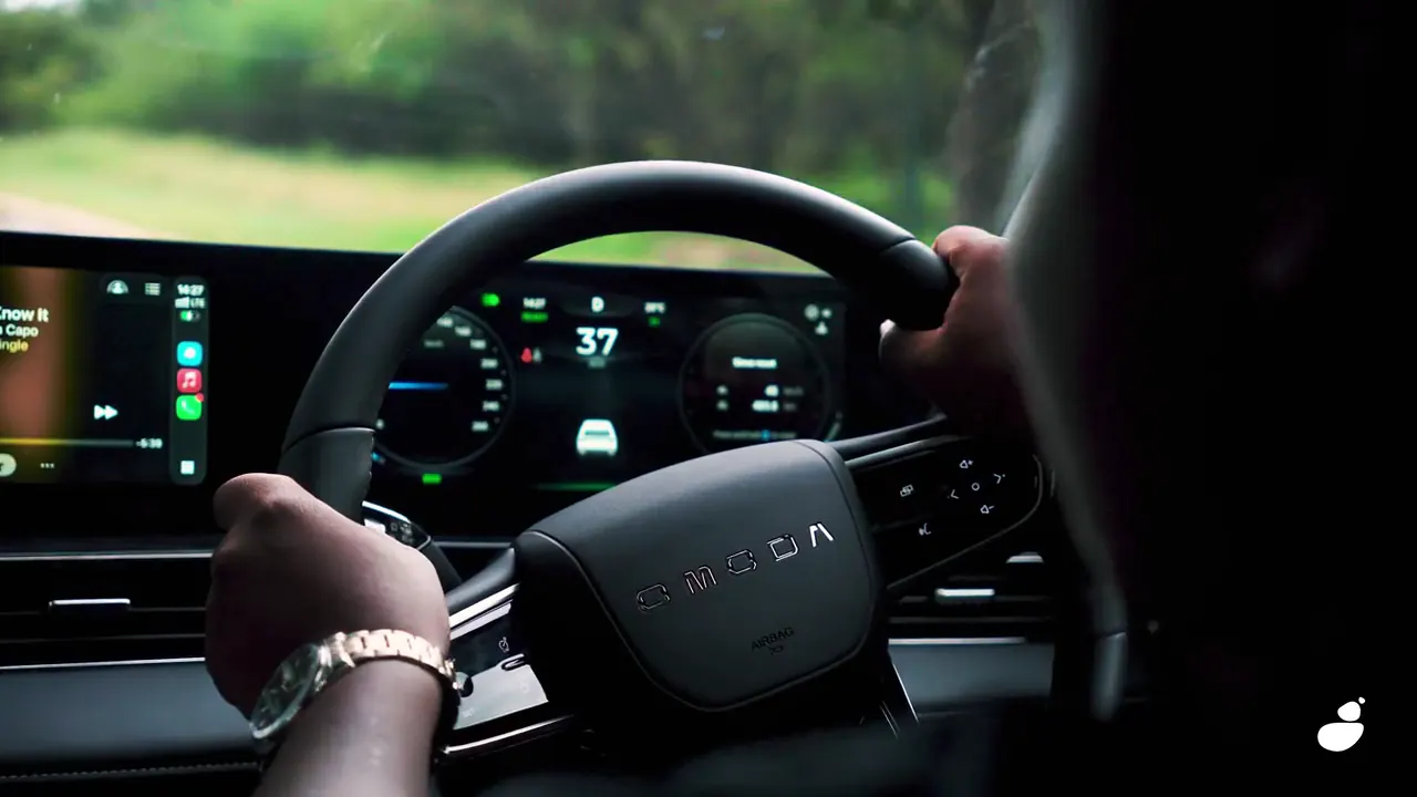 Driver's hands on the steering wheel in front of the Omoda C5's digital dashboard