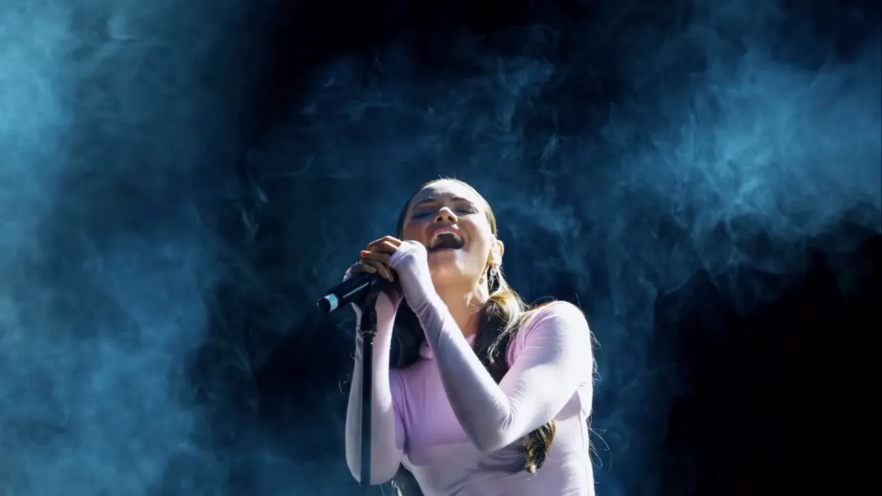 Singer performing into a microphone through blue stage smoke