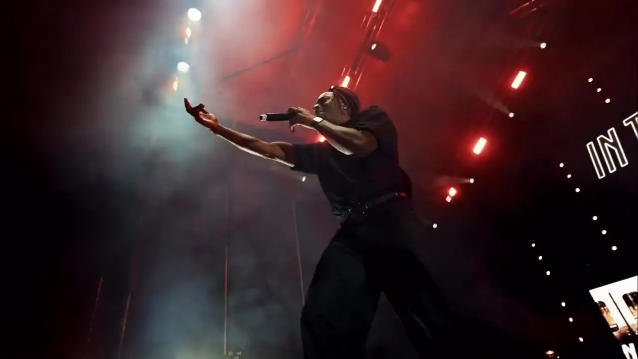Performer on stage reaching out to the crowd under red lights