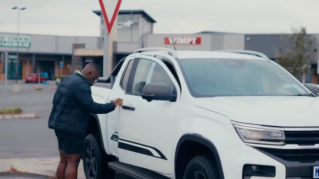 Presenter opening the door of a white Volkswagen Amarok